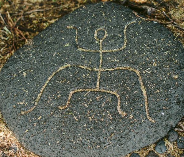 A rock with a simple petroglyph of a human figure with raised arms, possibly depicting a person or a symbol, etched into its surface.