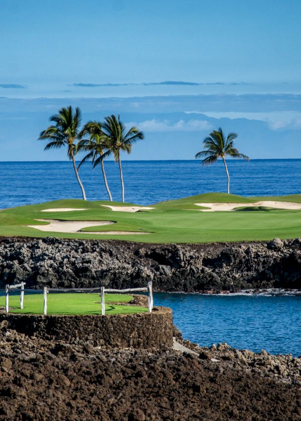 The image shows a scenic golf course set alongside the ocean, featuring palm trees, sandy bunkers, and clear blue skies in the background.